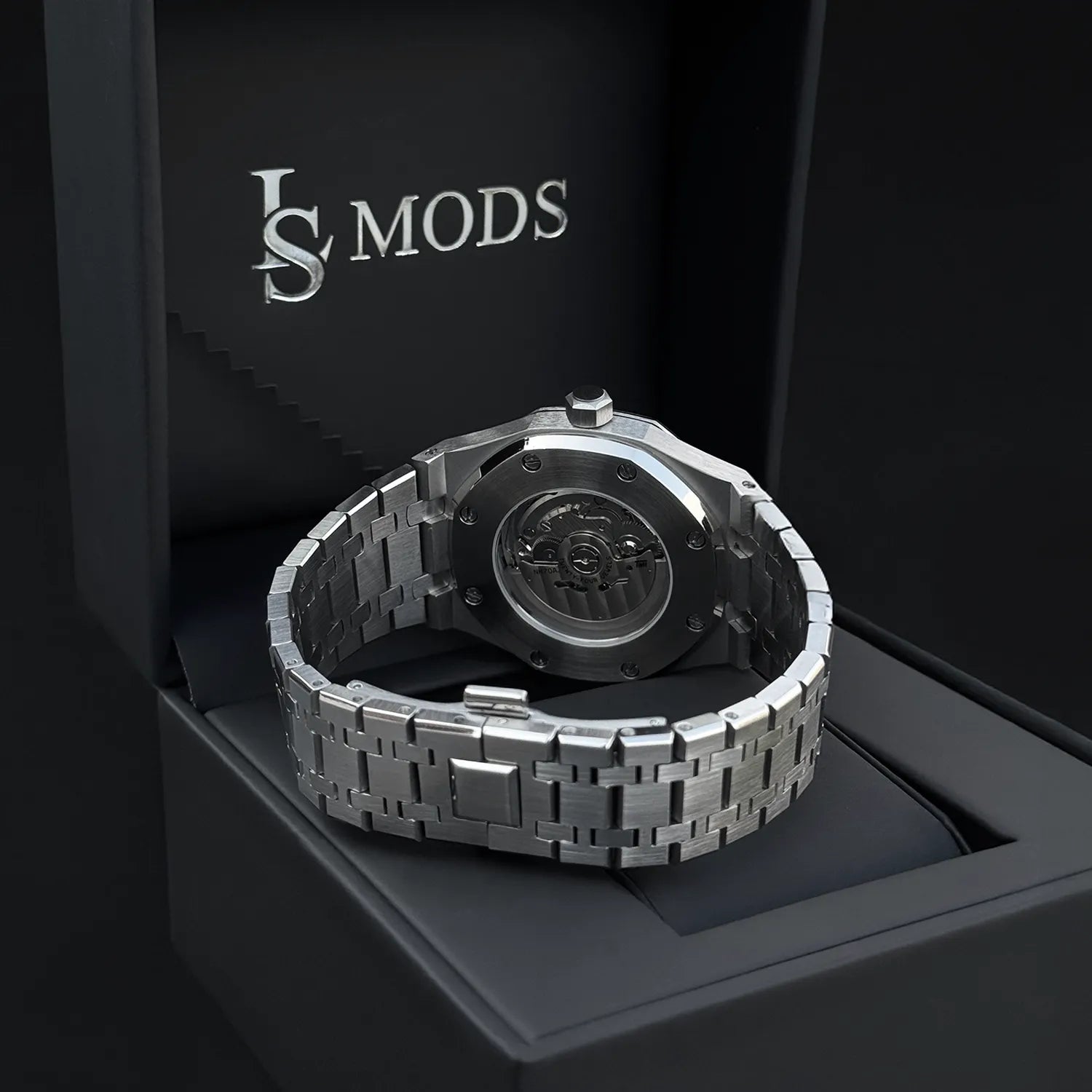 montre seikomod royal oak avec mouvement automatique apparent à travers le fond de boitier en verre saphir, posée sur une boîte en cuir noir lsmods