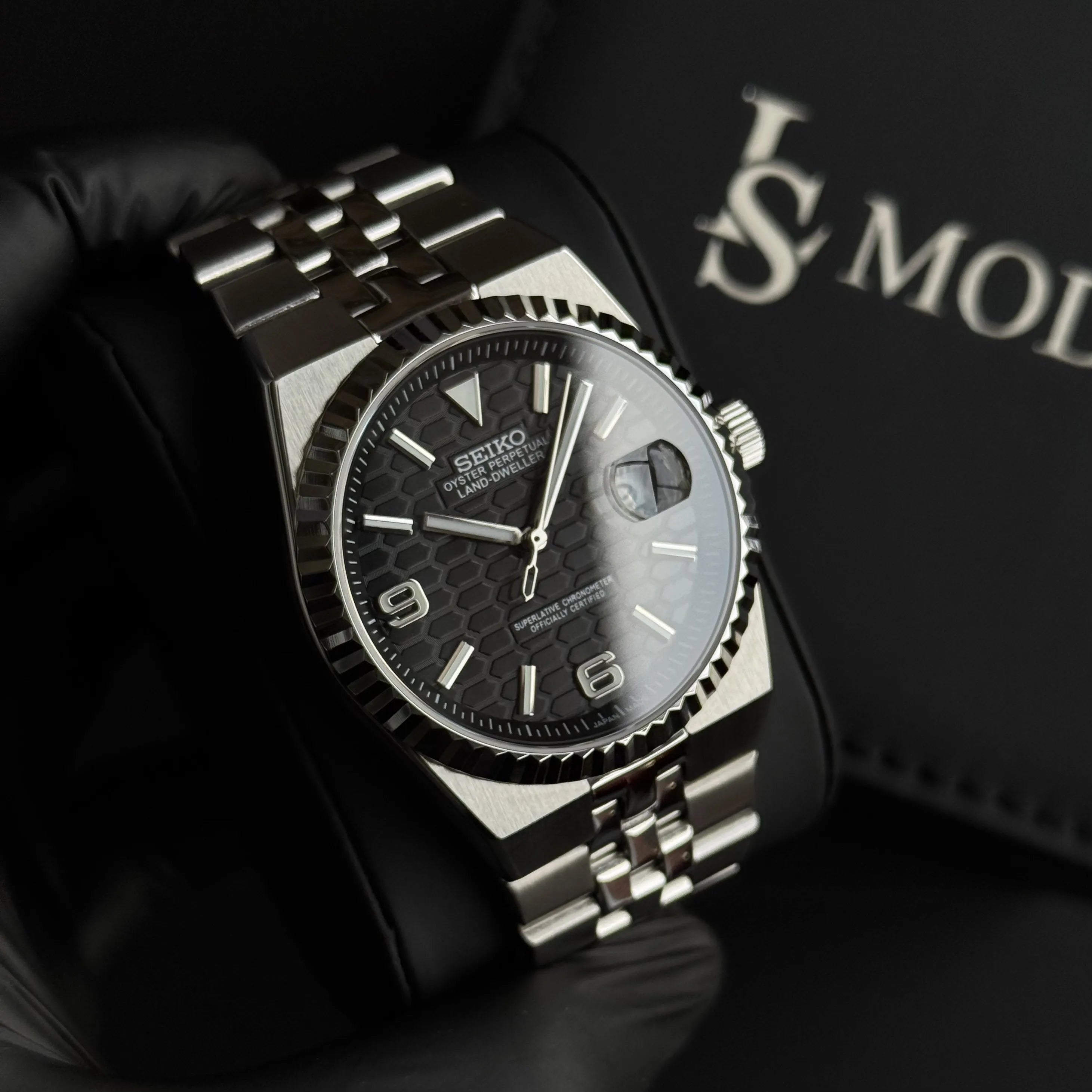 Montre Seiko Mod Land Dweller cadran noir nid d'abeille, mouvement automatique Seiko, boîtier et bracelet poli-brossé en acier inoxydable, présentée dans son écrin