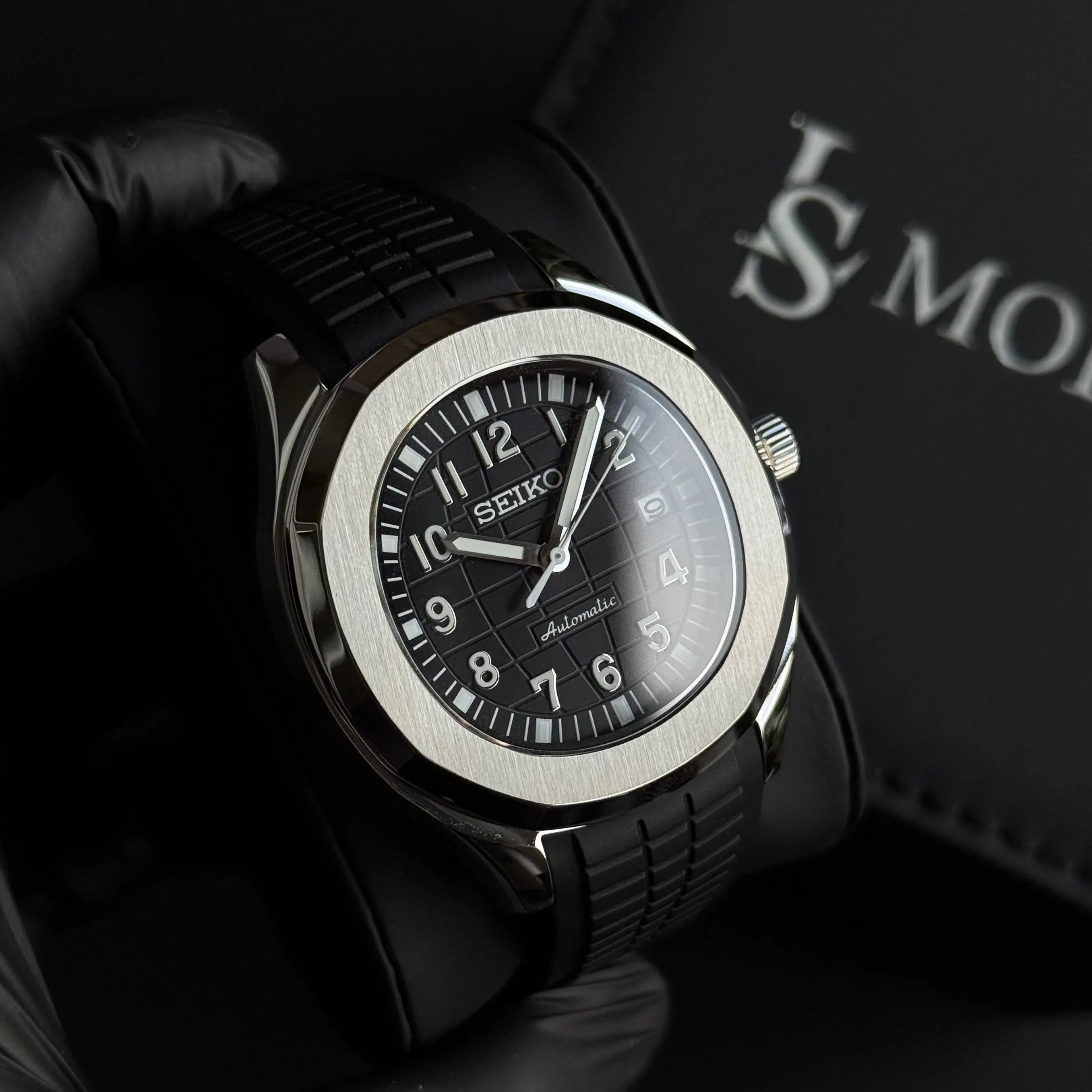 Montre Seiko Mod Aquanaut noire avec cadran texturé et boîtier acier inoxydable 40mm posée dans son écrin