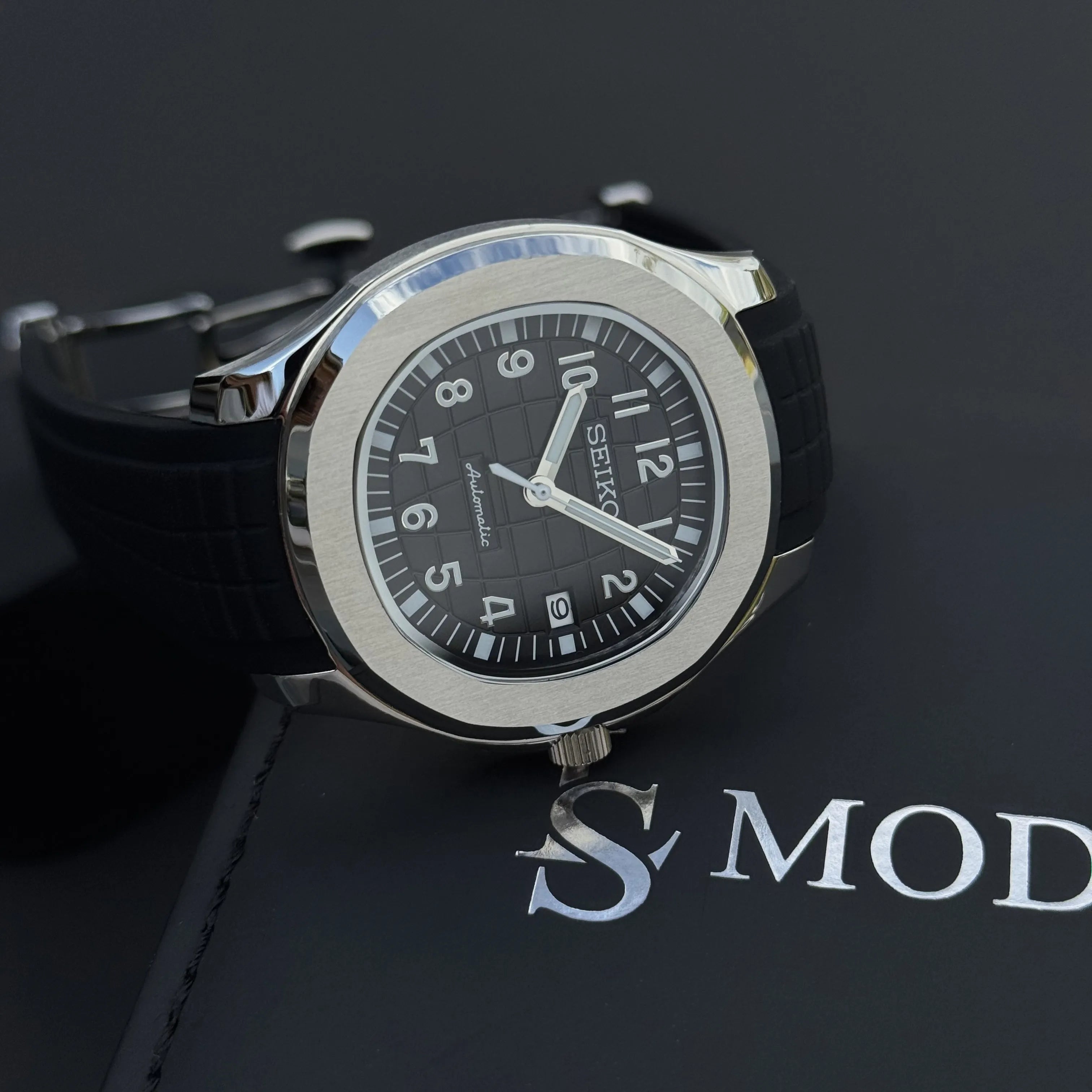 Montre Seiko Mod Aquanaut noire posée élégamment, cadran sport-chic et finition soignée
