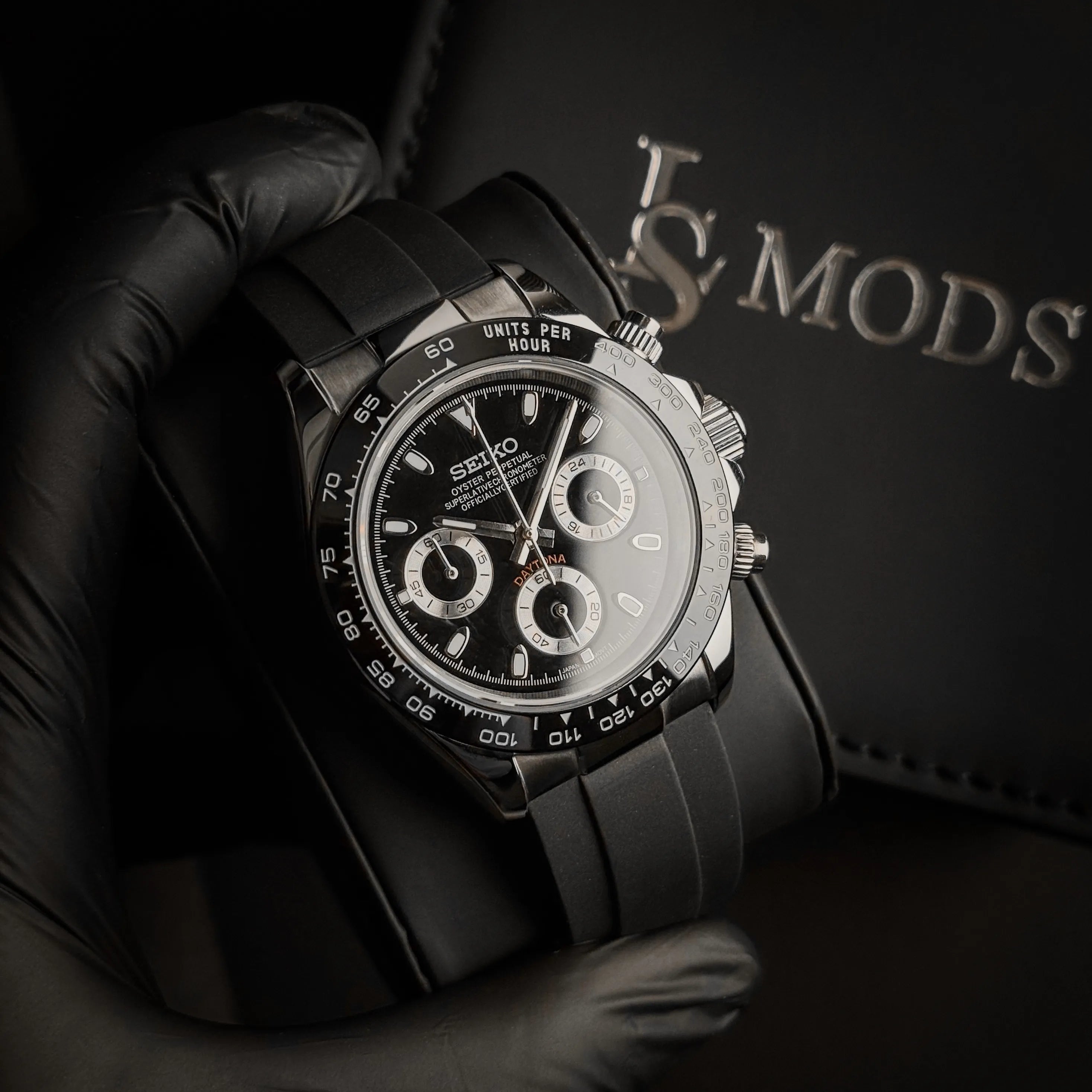 Montre Seiko Mod Daytona Oysterflex cadran noir présentée sur on écrin, acier inoxydable et mouvement Seiko VK63